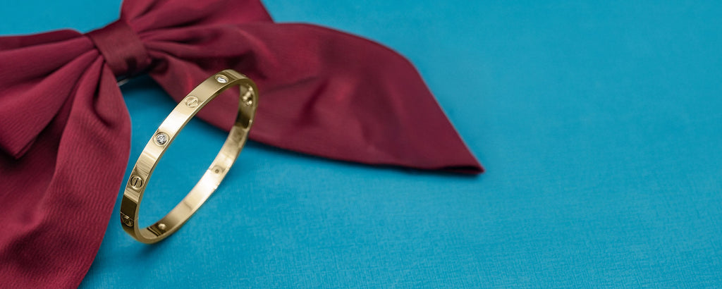 Gold bracelet on a red fabric bow against a blue background